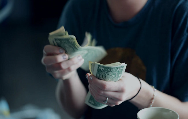 Hands counting a stack of dollar bills