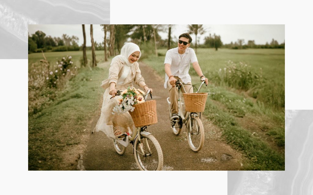 An engaged couple riding bikes with baskets. 