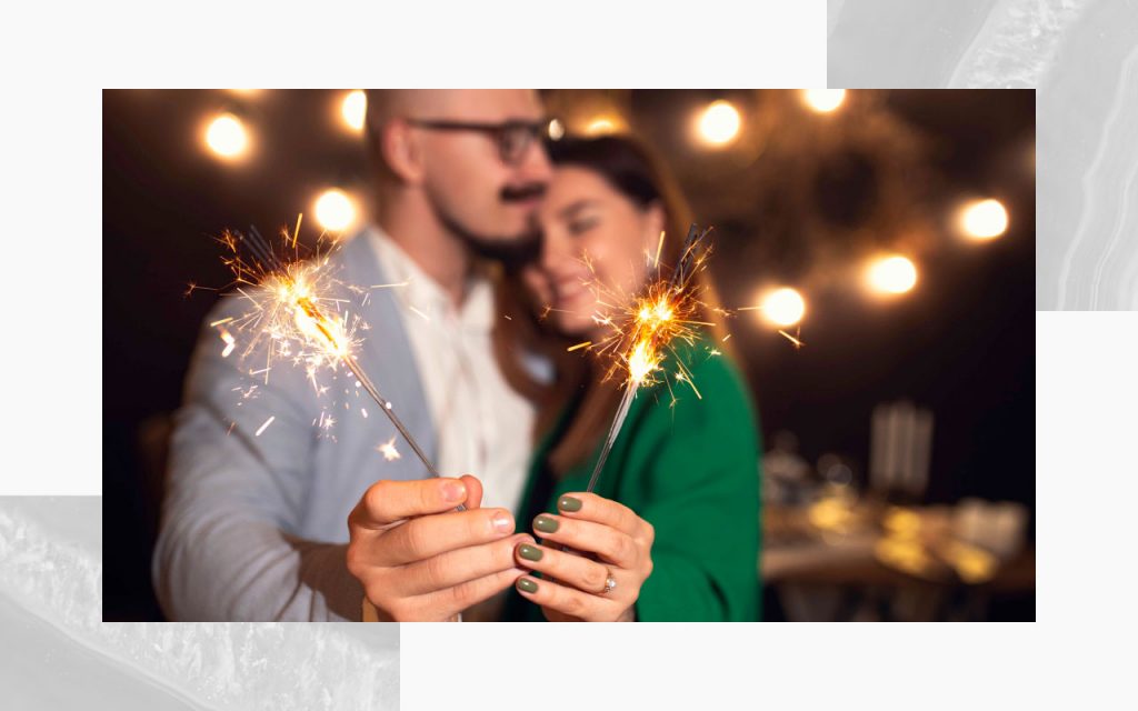 An engaged couple holding sparklers.