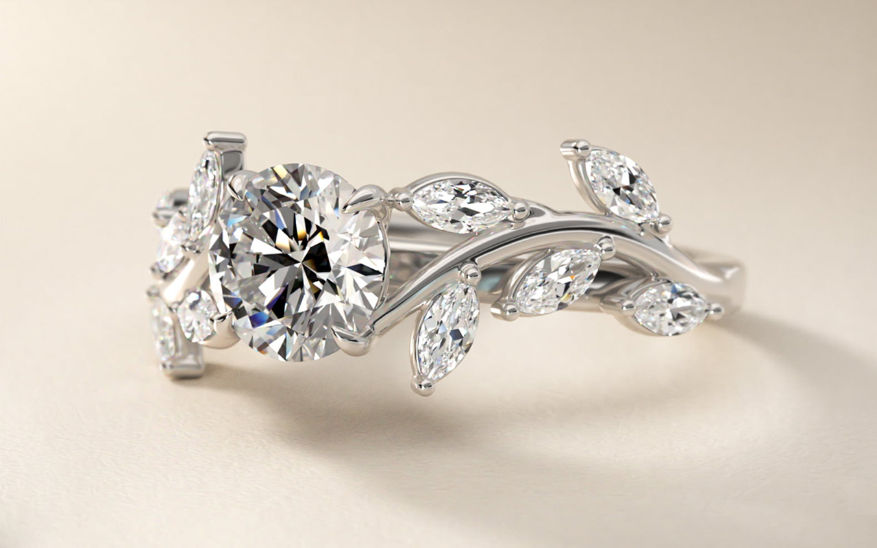 Side view of a romantic round and pear cluster diamond engagement ring highlighting an I colored diamond and leaf-inspired setting