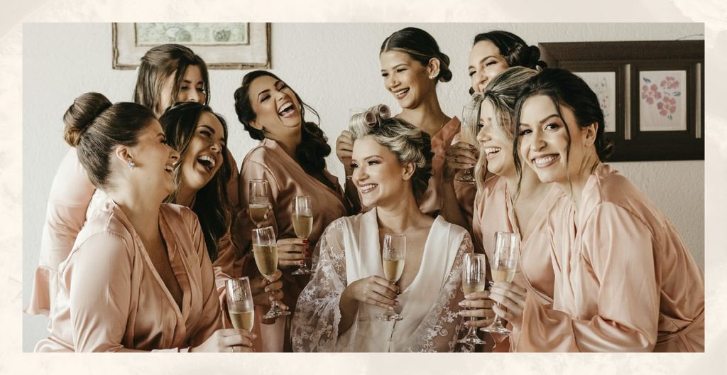 A bridal party gathers around the bride in matching pink loungewear.