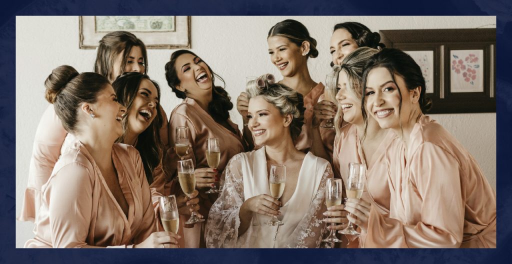 A bridal party gathers around the bride in matching pink loungewear.