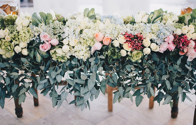 flowers and greenery on the back of wooden chairs