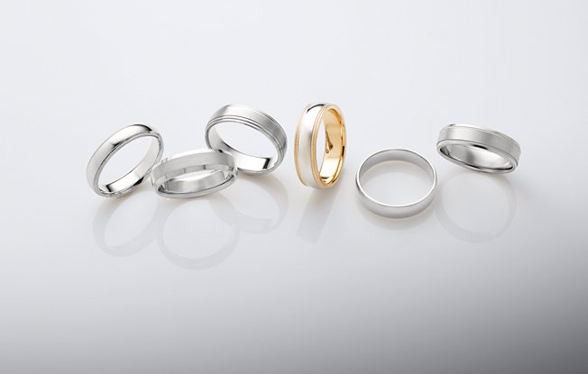 6 men's engagement rings of varying styles on a white background