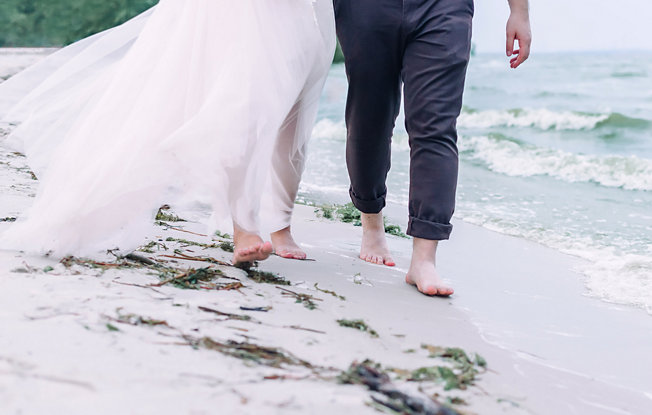 A bride and groom walking on the beach