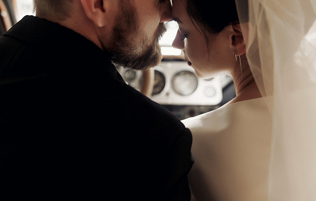 A bride and groom sitting close together in a car