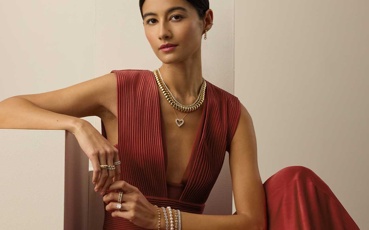 Model wearing layered gold necklaces and bracelets from the Blue Nile Modern Vintage Romance Collection