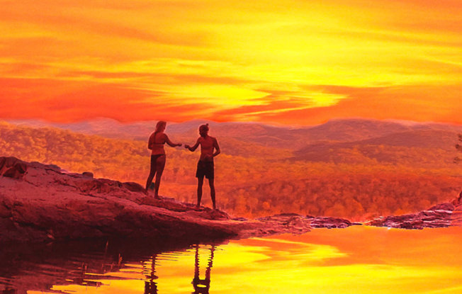 A couple on the beach in front of a colorful sunset