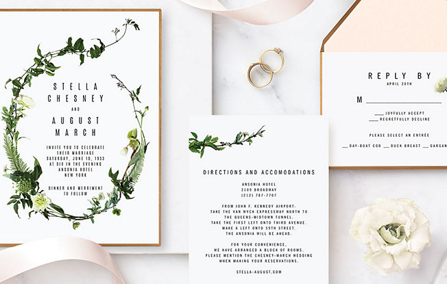 Wedding stationary and two wedding rings sit on a marble tabletop