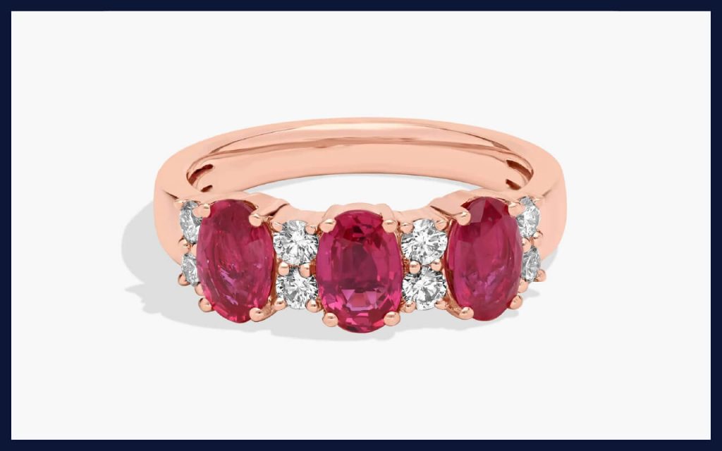 Three bright red rubies accented with white stones in rose gold, a bold option for non-traditional engagement ring stones