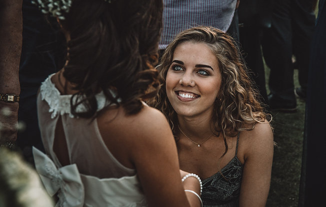 A woman smiling at a child wearing a white flower girl dress