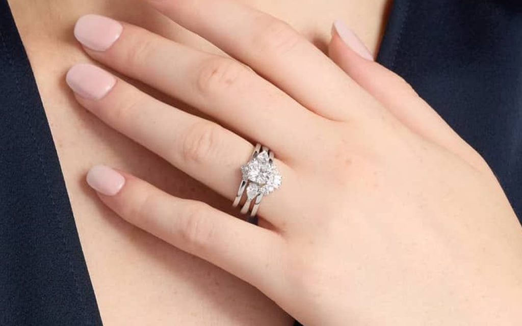 Tall engagement rings can sit beside and above wedding rings for a cohesive look