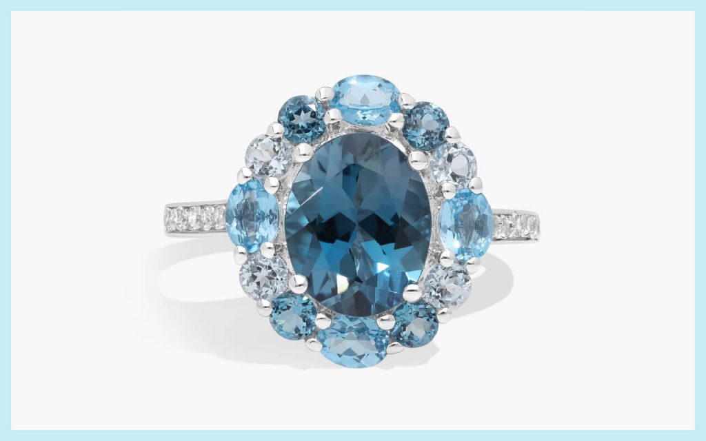 Oval blue topaz surrounded by lighter blue stones, offering a cool-toned look among alternative engagement stones